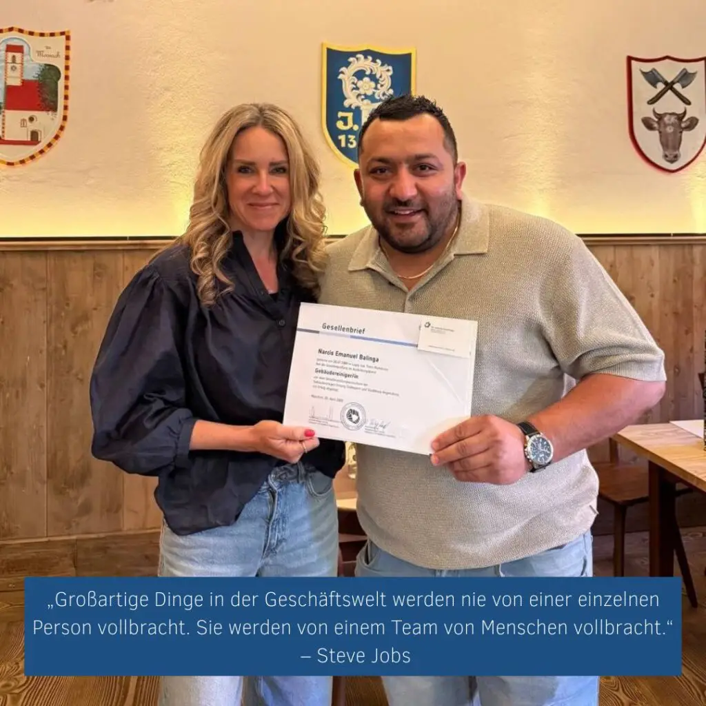 Constance Rettler überreicht Emanuel Balanga den Gesellenbrief zum Gebäudereiniger – beide lächeln stolz in die Kamera. Das Bild zeigt persönliche Wertschätzung, Teamgeist und gelebte Nachwuchsförderung bei DRS. Im Hintergrund Wappen und Holzvertäfelung eines feierlichen Raums. Zitiert wird Steve Jobs: „Großartige Dinge in der Geschäftswelt werden nie von einer einzelnen Person vollbracht. Sie werden von einem Team von Menschen vollbracht.
