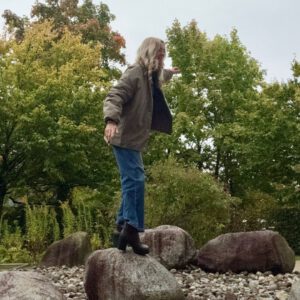 Constance Rettler balanciert auf einem Stein – Sinnbild für den „Glass Cliff“: Frauen in Führungsrollen zwischen Risiko und Verantwortung.