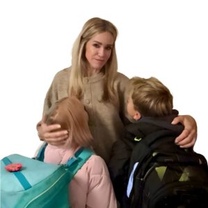 Constance Rettler, Unternehmerin und Geschäftsführerin der Dr. Rettler Service GmbH, steht im Flur mit ihren beiden Kindern, die Schulrucksäcke tragen. Das Bild zeigt einen warmen, authentischen Moment zwischen Mutter und Kindern – Sinnbild für Balance, Verantwortung und Führungsstärke im Familien- und Berufsalltag.